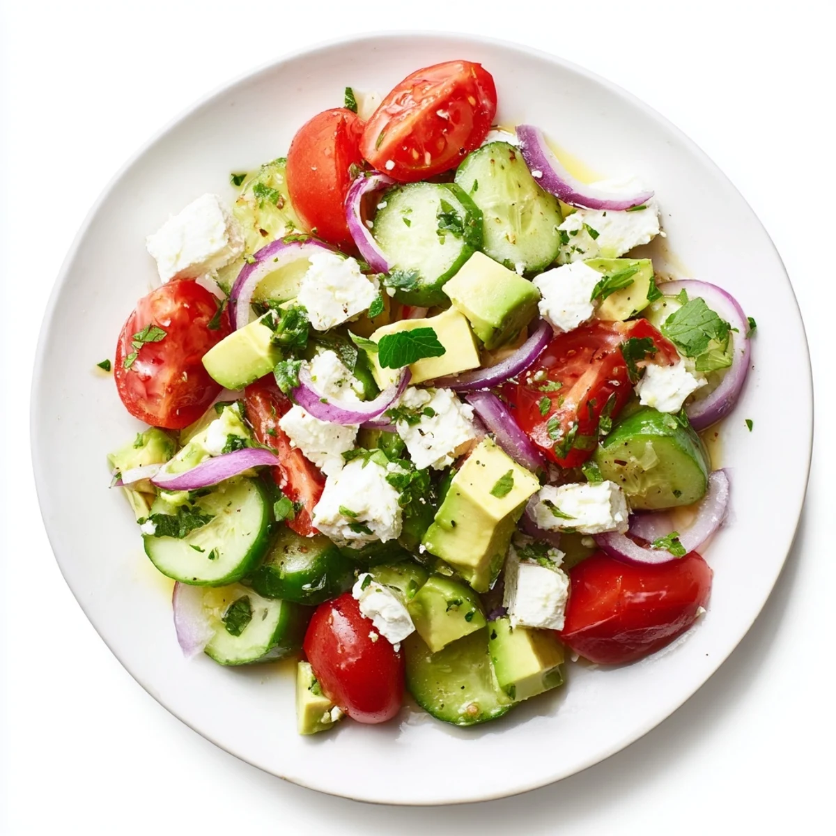 Fresh Cucumber, Tomato, and Avocado Salad with feta, glistening with a vibrant lemon-olive oil dressing.