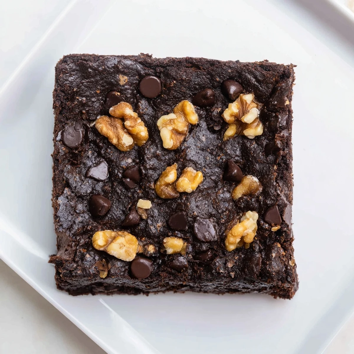 A close-up of rich, chocolate-laden Fudgy Walnut Brownies dotted with walnuts, ready to be cut and served.
