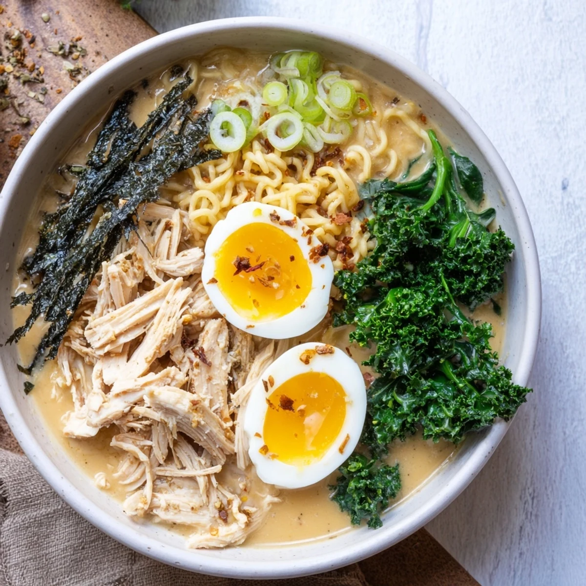 Savory and creamy chicken ramen, enhanced with Kewpie mayo, showcasing vibrant greens and a delicious soft egg.