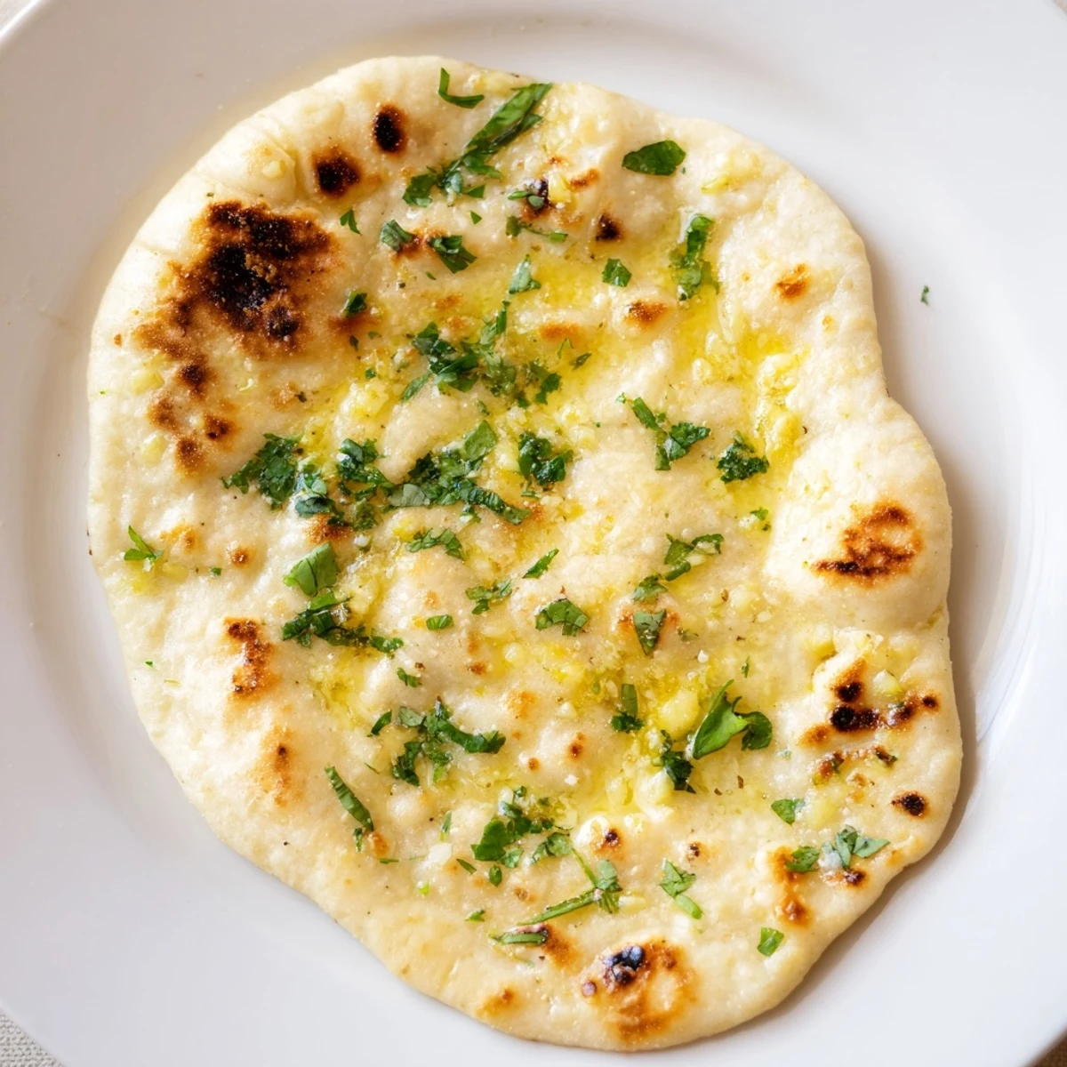 Golden-brown Homemade Garlic Naan Bread, brushed with garlic butter, ready for dipping into curry.