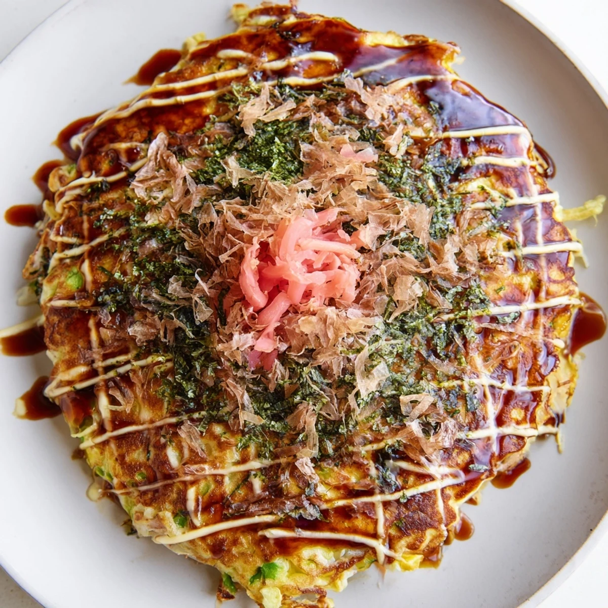 Golden-brown Japanese Okonomiyaki Pancakes topped with bonito flakes and aonori.  