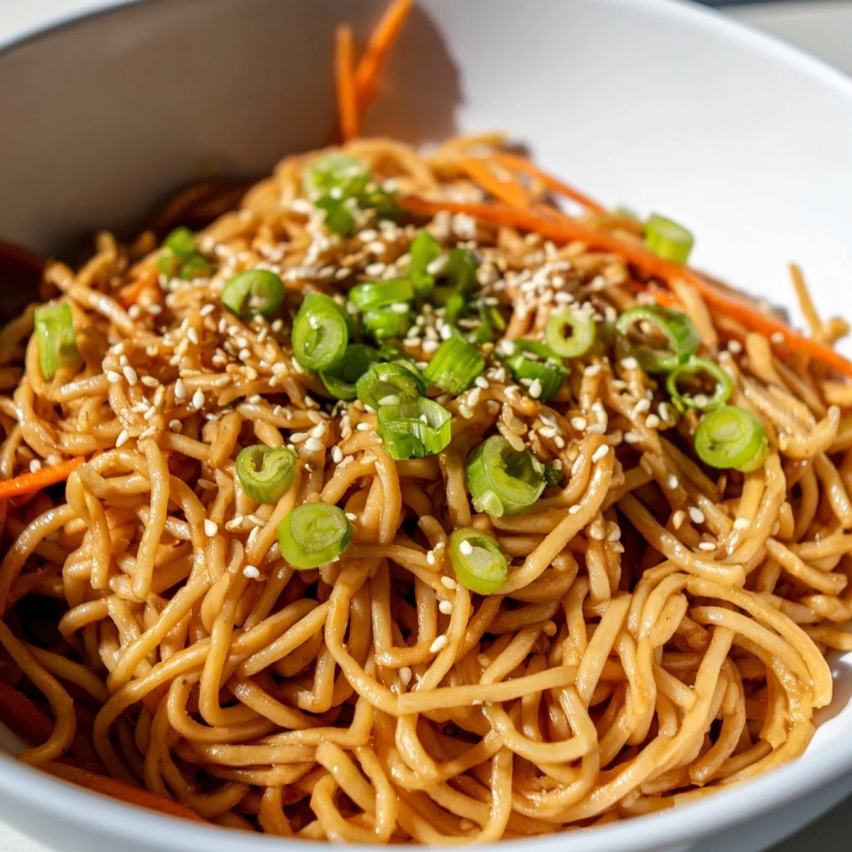 Hearty Asian Garlic Noodle Bowl garnished with fresh cilantro, scallions, and sesame seeds, served in a ceramic bowl for a quick meal.