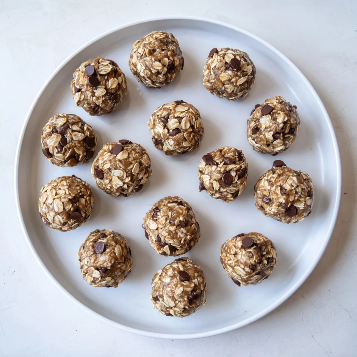 Freshly rolled Banana Chocolate Chip Energy Balls on a parchment-lined tray, showcasing their natural sweetness and chewy texture.
