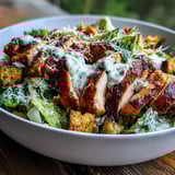 Bright Caesar Chicken Bowl served with shaved parmesan, grilled chicken, and golden croutons on a bed of fresh romaine lettuce.