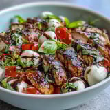 Fresh basil and a tangy balsamic reduction add bright flavor to a served Caprese Chicken Bowl with ripe tomatoes and mozzarella.