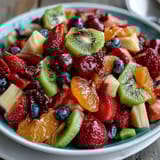 Vibrant rainbow fruit platter with coconut whipped cream, perfect for healthy desserts or brunch spreads.