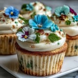 Spring cupcakes decorated with colorful edible blooms and creamy vanilla frosting, perfect for seasonal celebrations.  