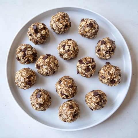 Freshly rolled Banana Chocolate Chip Energy Balls on a parchment-lined tray, showcasing their natural sweetness and chewy texture.