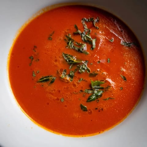 Steam rising from the warm, smooth Comfort Soup with fresh basil garnish, a cozy delight.