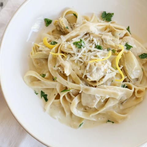 Vibrant photo of Creamy Lemon Artichoke Pasta, garnished with fresh basil, ready for dinner.