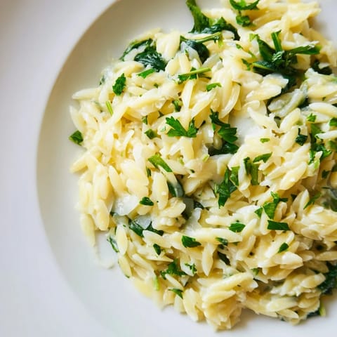 A close-up shot of rich, creamy one-pot orzo, with melted cheese and vibrant green spinach.