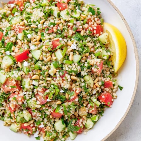 Close-up of a refreshing Tabbouleh Grain Bowl, with bulgur wheat and a bright lemon dressing poured over.