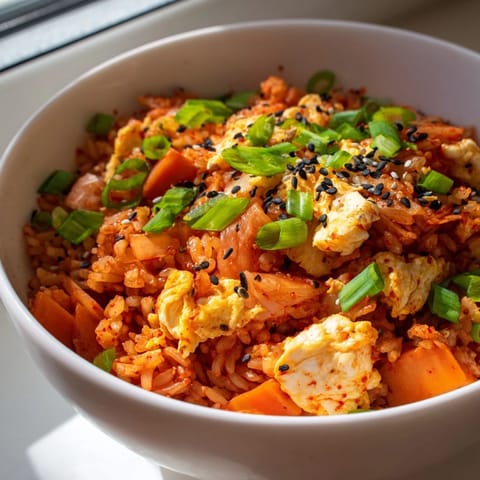 Steaming Spicy Kimchi Fried Rice in a hot skillet, chopped kimchi and green onions mixed into fluffy rice with a glossy finish.