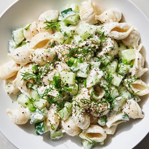 Creamy Cucumber Crunch Pasta Salad in a white bowl, loaded with diced cucumbers, green onions, dill, and everything bagel seasoning.