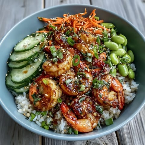 Sizzling shrimp for an Asian Shrimp Bowl garnished with scallions and sesame seeds, drizzled with tangy ginger-sesame dressing.
