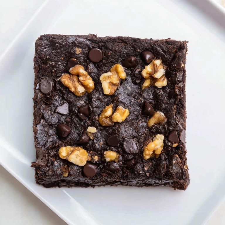 A close-up of rich, chocolate-laden Fudgy Walnut Brownies dotted with walnuts, ready to be cut and served.