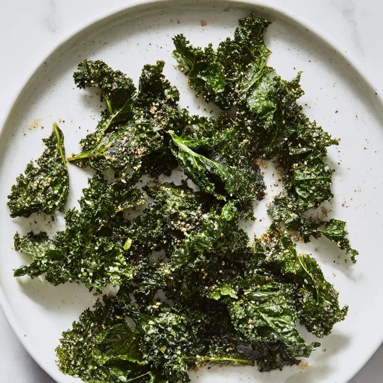 Freshly seasoned crispy kale chips, a baked snack with smoky paprika and garlic flavors.