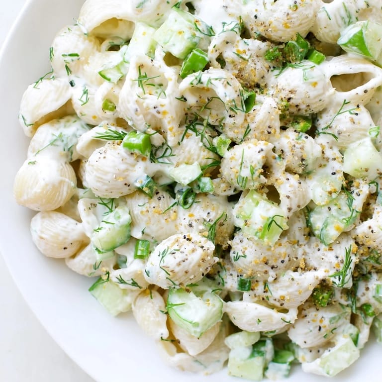 A chilled bowl of Cucumber Crunch Pasta Salad tossed in creamy dressing, featuring tender small shell pasta and crisp vegetables.